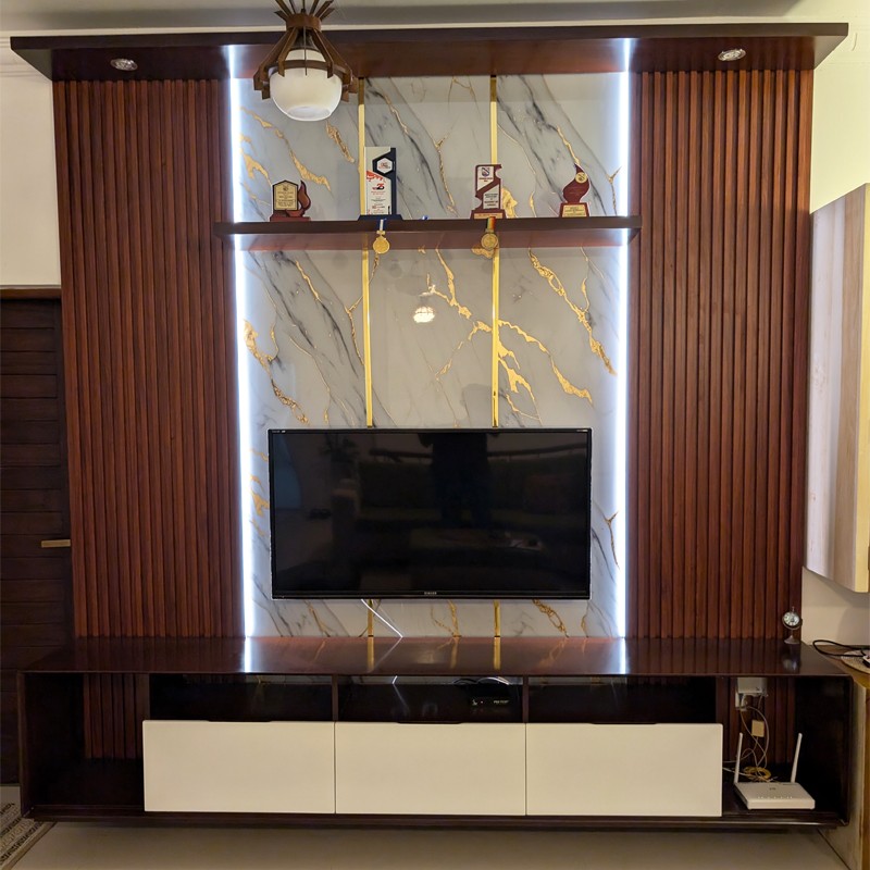 Elevate your living space with this stunning 9ft wide and 9ft high wall-mounted TV console, designed for both elegance and functionality. Featuring a luxurious combination of dark wood tones, vertical fluted panels, and a marble-effect back panel with gold accents, this unit adds a premium touch to any interior. Integrated ambient LED lighting highlights the textures and creates a cozy atmosphere. The spacious bottom unit includes sleek white cabinets for concealed storage and open shelves for electronics. Ideal for modern homes, this console is a perfect blend of style and practicality.